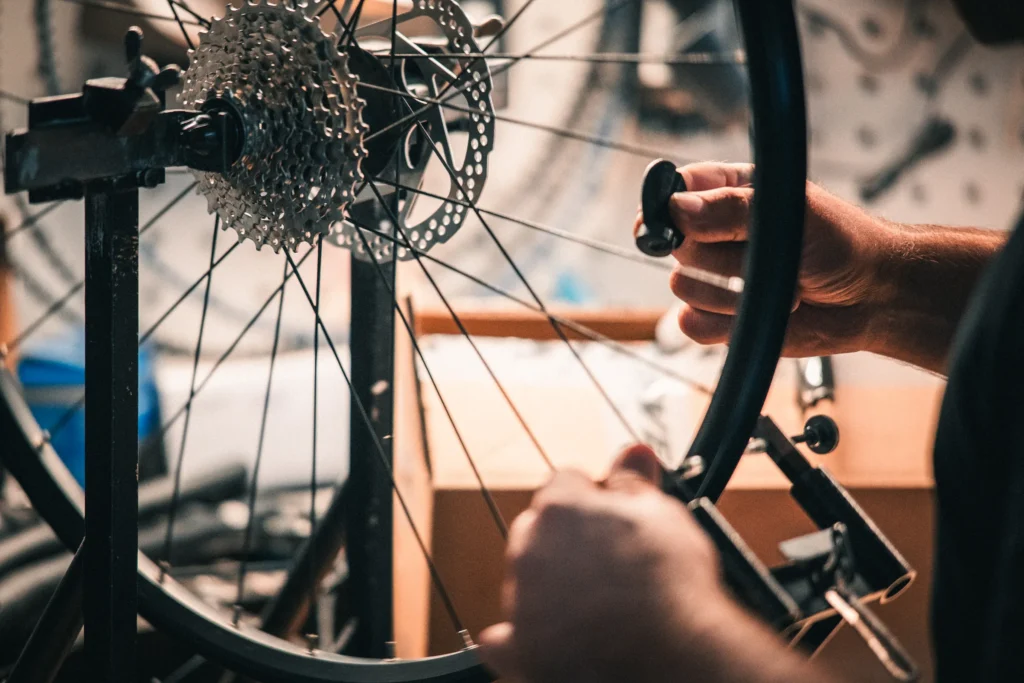 Fahrradmechaniker mit Laufrad am Montageständer